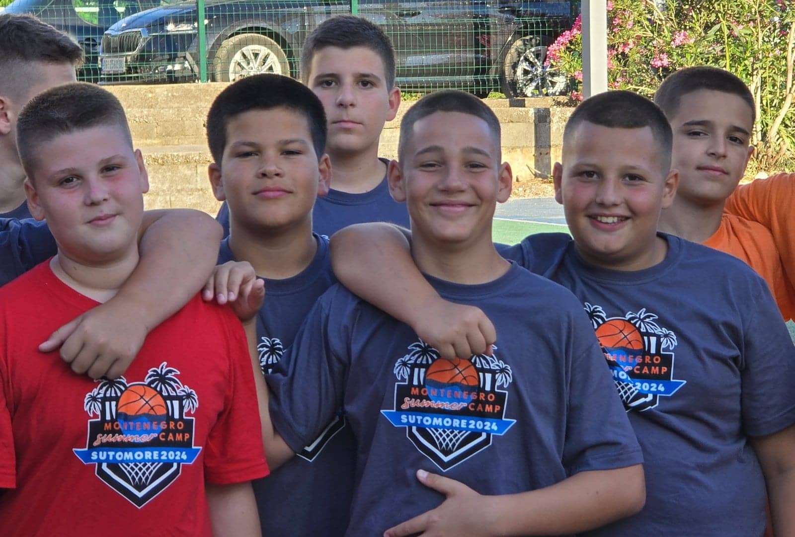 Smiling campers in camp shirts, arms around each other's shoulders