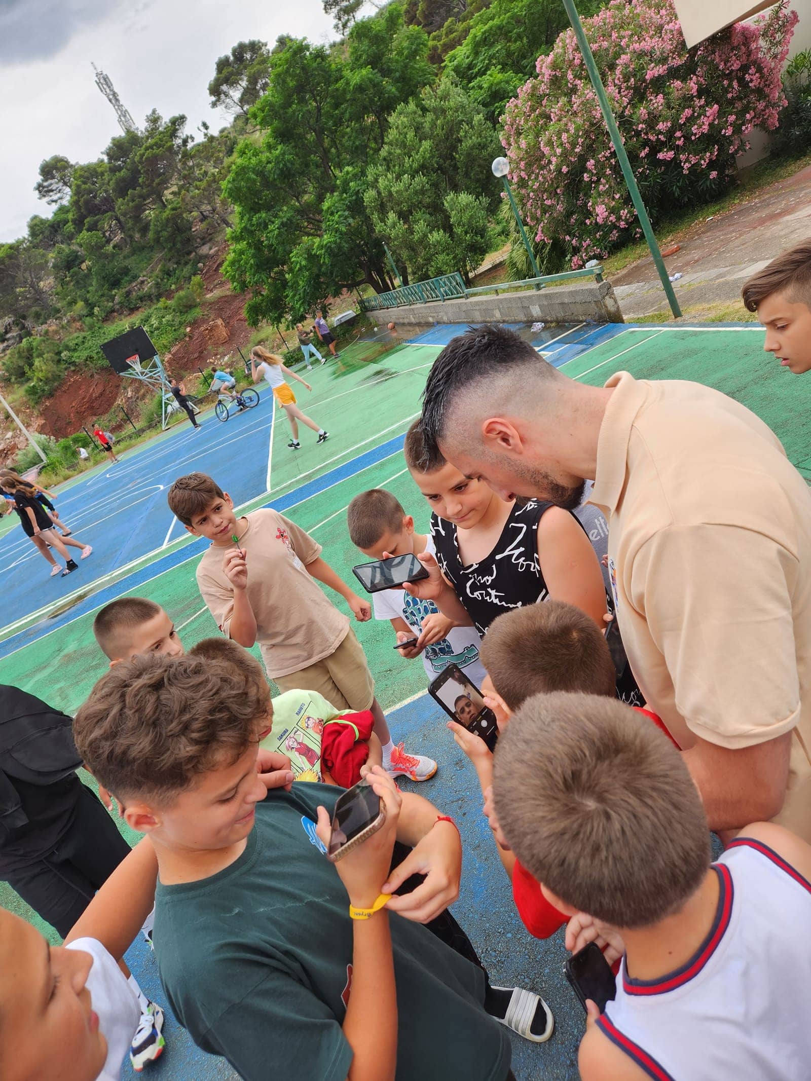 A guest player taking photos with campers on the court