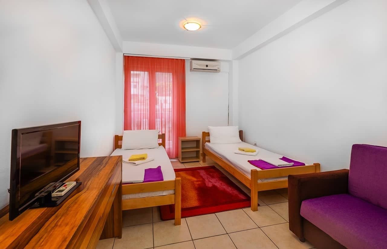 A twin room with air conditioning, a TV and a balcony door