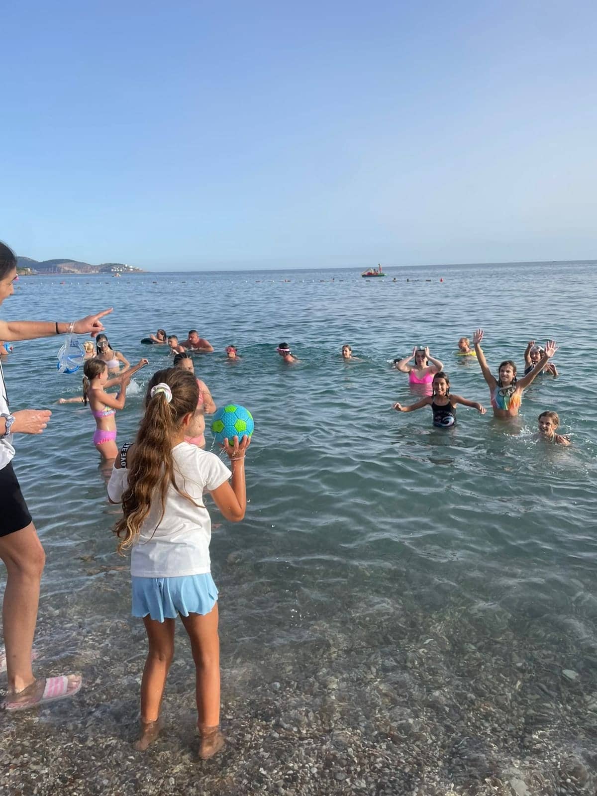 Campers swimming in the clear Adriatic with the Sutomore coastline behind